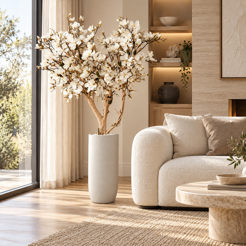 8ft White Magnolia Tree in Matte Beige St. Tropez Planter — styled in a living room beside a sofa